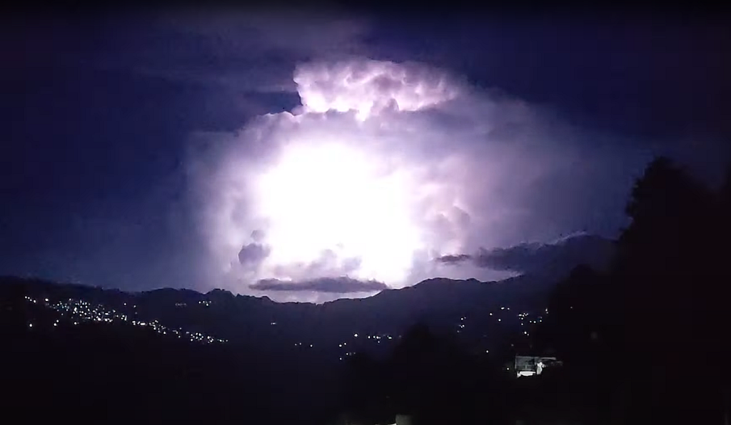 A nighttime thunderstorm flashes in front of the high peak of the Cerro Zempoaltepetl.